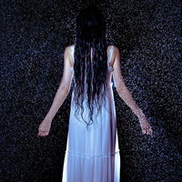激しい雨に打たれてびしょ濡れになる白いワンピース姿の女性の写真