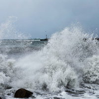 防波堤の消波ブロックに打ち付ける荒波と波飛沫の写真