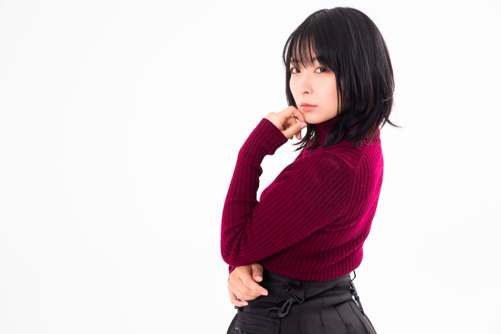 赤い服を着た黒髪の女性が腕組みをしながら振り返っている
