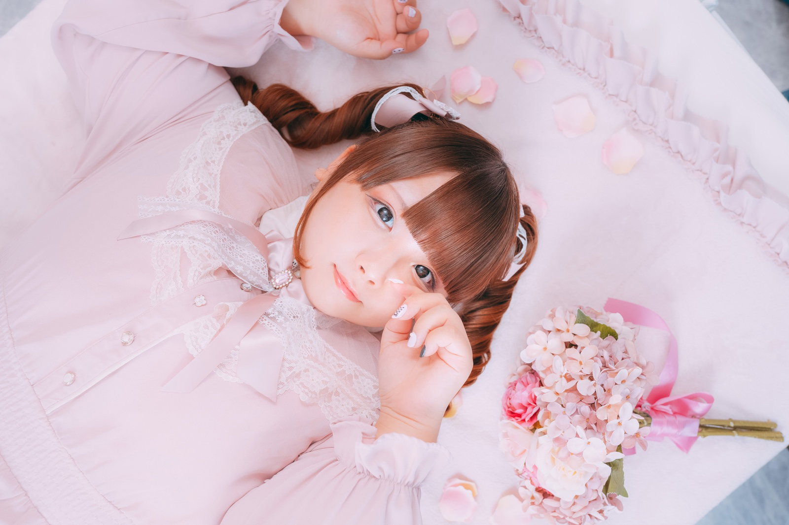 ピンクのドレスを着てピンクのバラを持ち寝転ぶ女性［モデル：あづき］