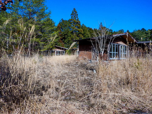 青空の下に佇むボロボロの廃コテージ。朽ちた古い小屋