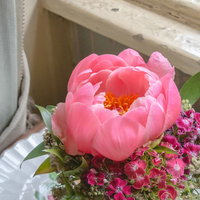 窓辺に置かれたピンクの芍薬を使ったフラワーアレンジメントの写真