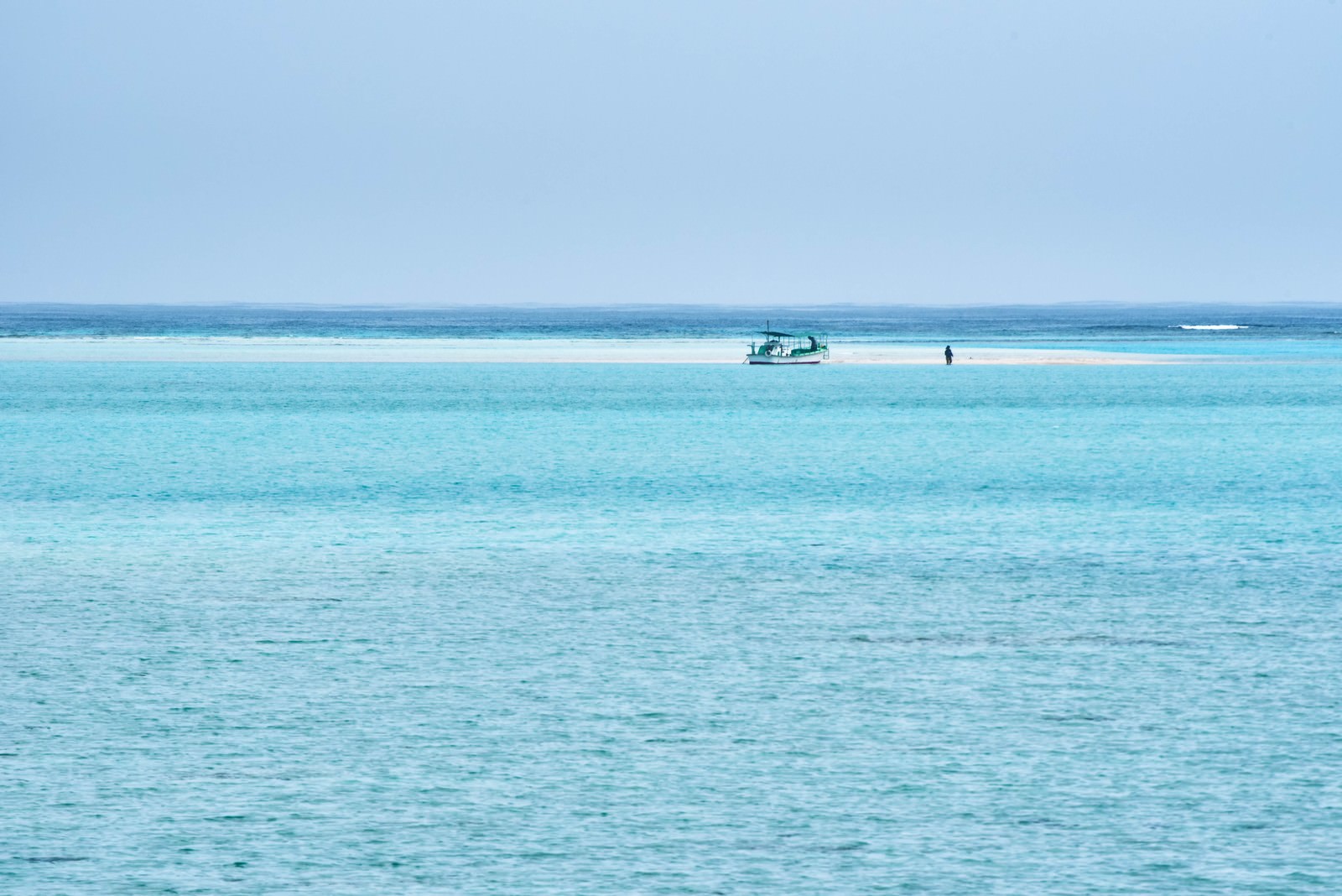 干潮時に現れる幻の浜辺に停泊する白い船とエメラルドグリーンの海