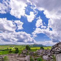 美ヶ原の登山道脇に積まれたケルンと高原の景観の写真