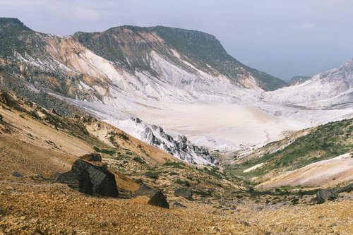 爆裂火口と緑に覆われた船明神山の荒涼とした山肌