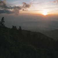 鳳凰三山の山肌に差し掛かるご来光と朝焼けの風景の写真