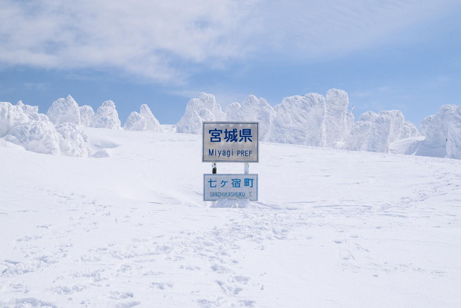 雪に覆われた蔵王の樹氷と宮城県の県境看板
