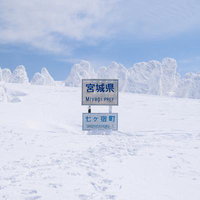 雪に覆われた宮城県七ヶ宿町の県境看板と足跡の写真