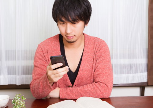 スマホのインカメラでVネックの開き具合をチェックする男性