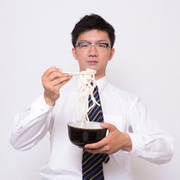 素うどんをすする眼鏡をかけたビジネスマンの写真