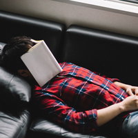 技術書をアイマスクにして爆睡する新米プログラマーの写真