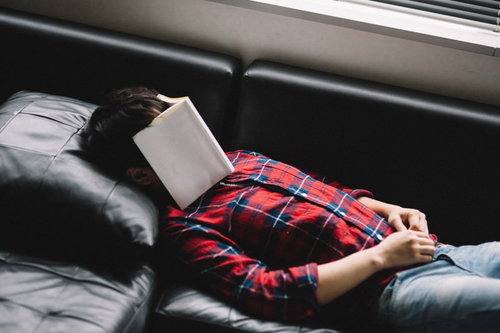 技術書をアイマスクにして爆睡する新米プログラマー