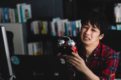 出勤72時間後、疲れ切った表情の男性の労働過多の実態