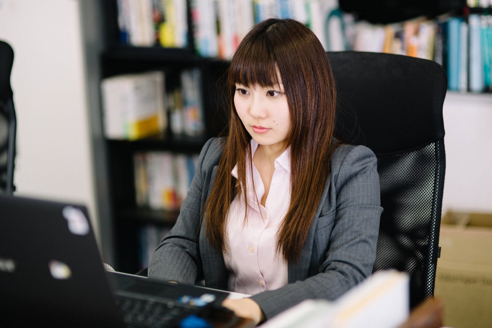 オフィスでノートパソコンに向かって作業する女性［モデル：Lala］