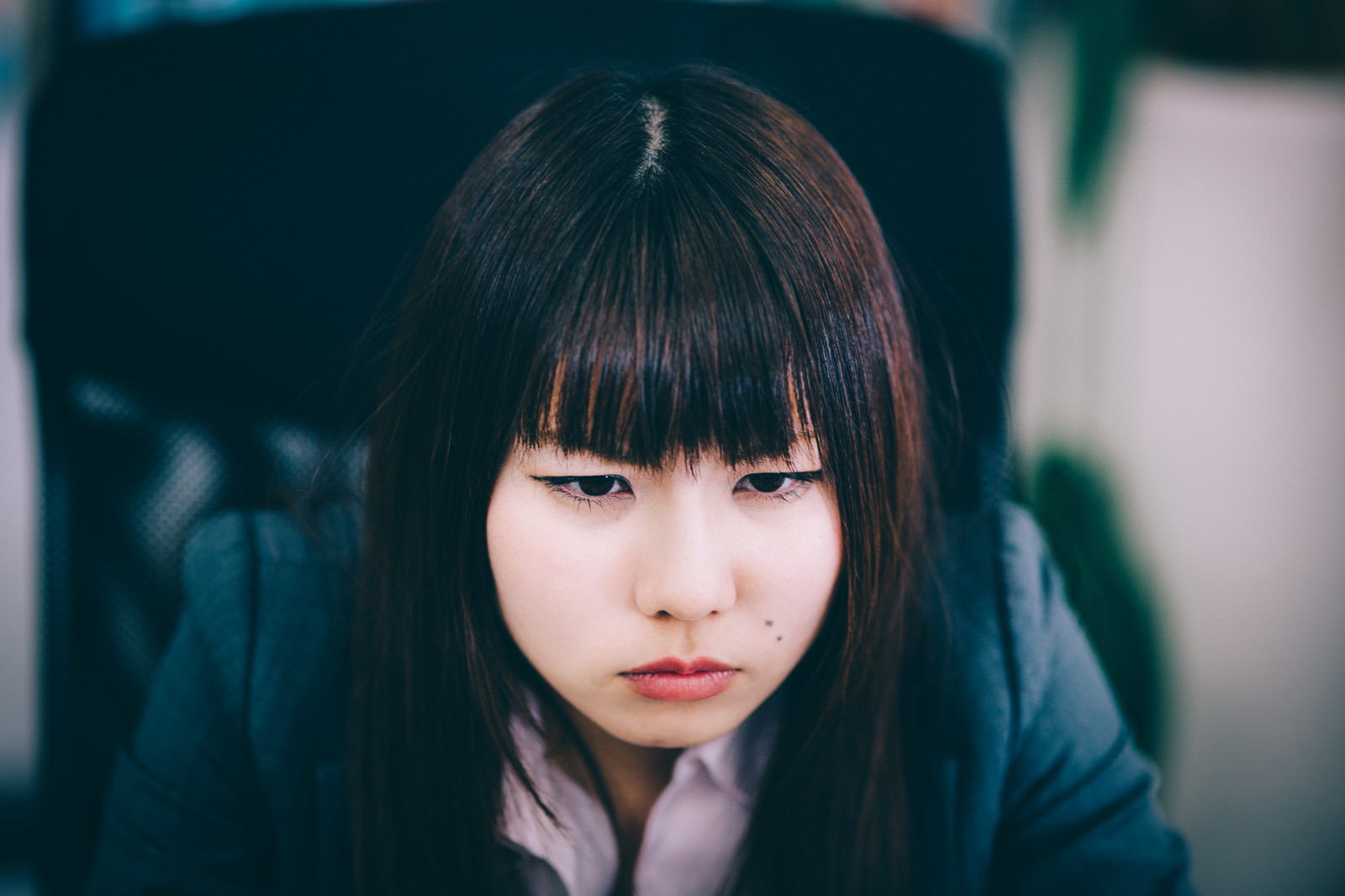 下を向いて目を閉じた落ち込んだ表情の若い女性社員のポートレート［モデル：Lala］