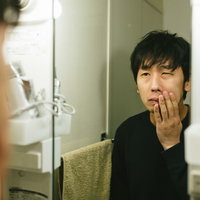 洗面台の鏡を見つめてカミソリ負けに悩む男性の写真