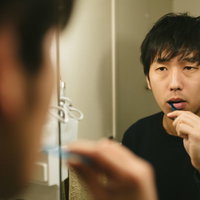 室内で膝を抱えてふさぎ込む男性の写真