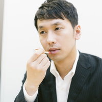 新製品の口紅を試す化粧品会社の男性社員のメンズビューティーの写真