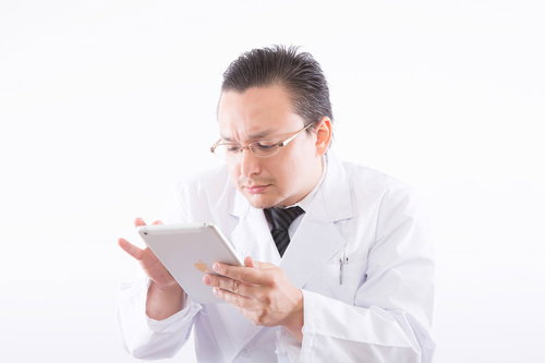 タブレットで電子カルテを確認する白衣の医者