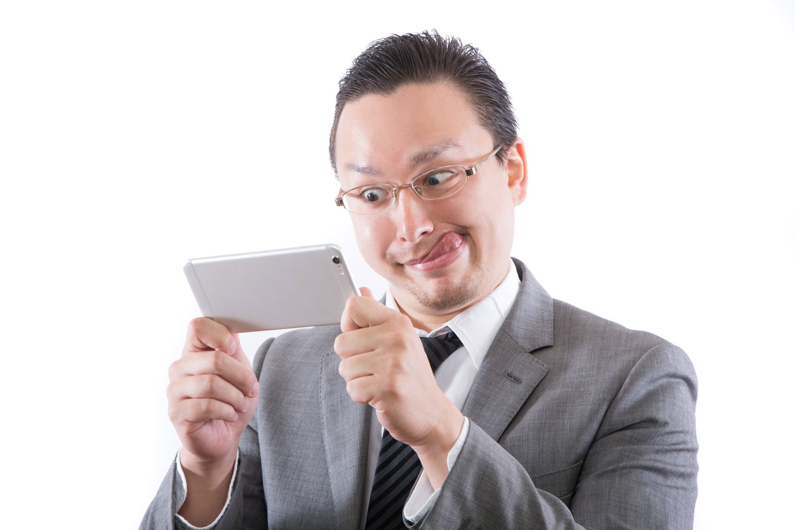 タブレットを見て舌を出す不適切なスーツ男性［モデル：Max_Ezaki］