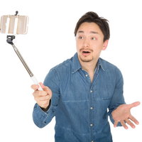 スマートフォンで自撮り動画を撮りながら驚く表情の外国人男性の写真