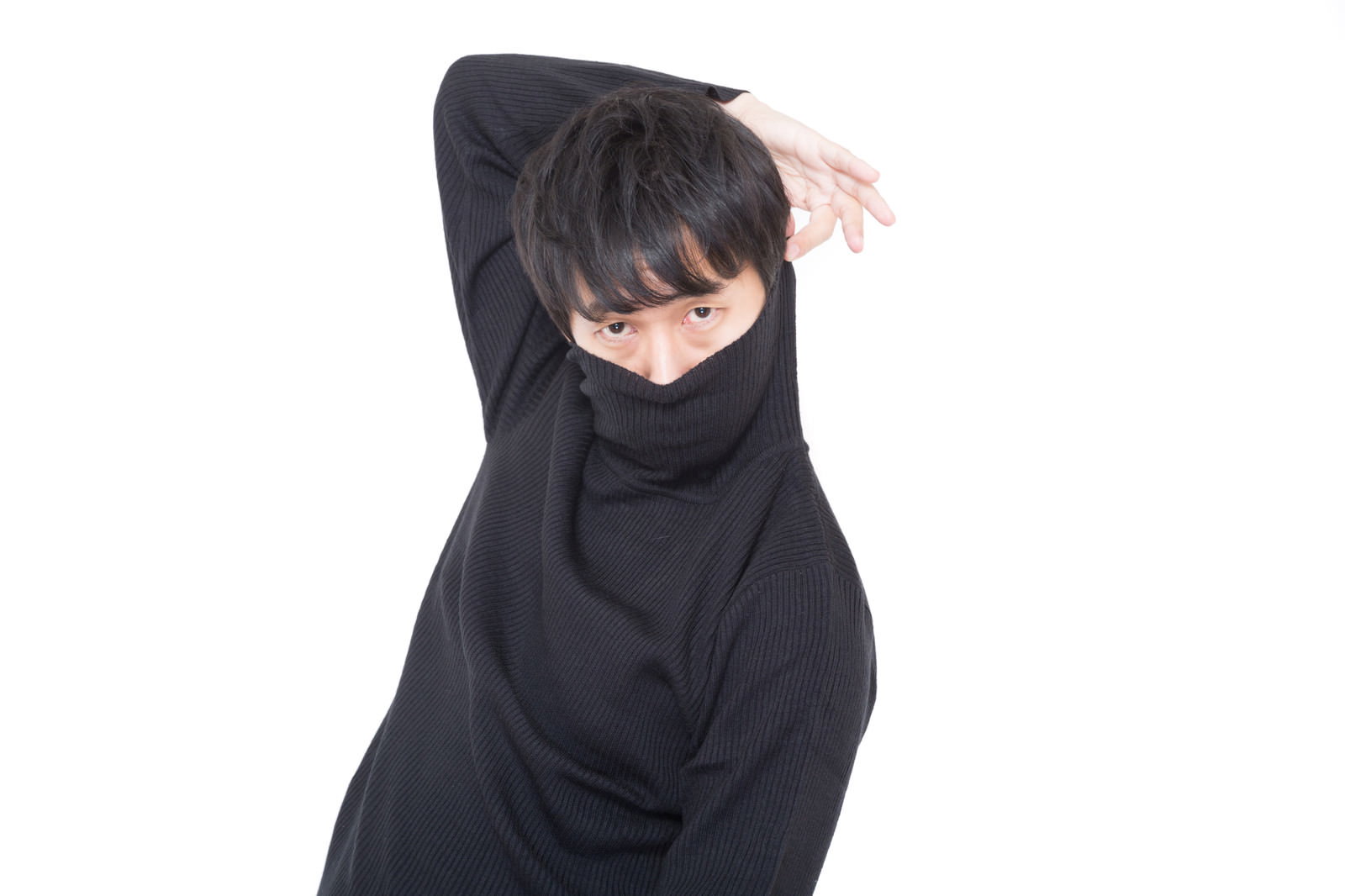 黒いタートルネックを頭からかぶり、腕を後ろに回して体をねじる男性［モデル：大川竜弥］