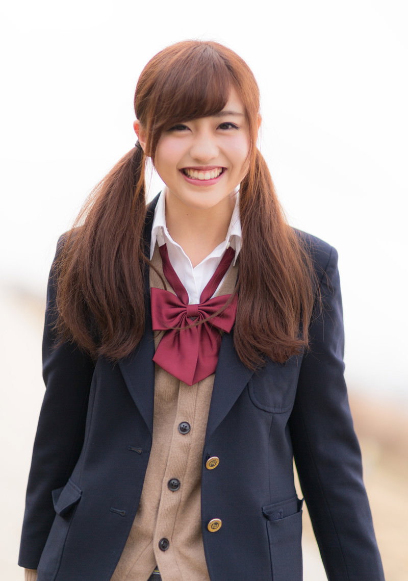 紺色ブレザーとえんじ色リボン姿で笑顔の女子高生［モデル：河村友歌］