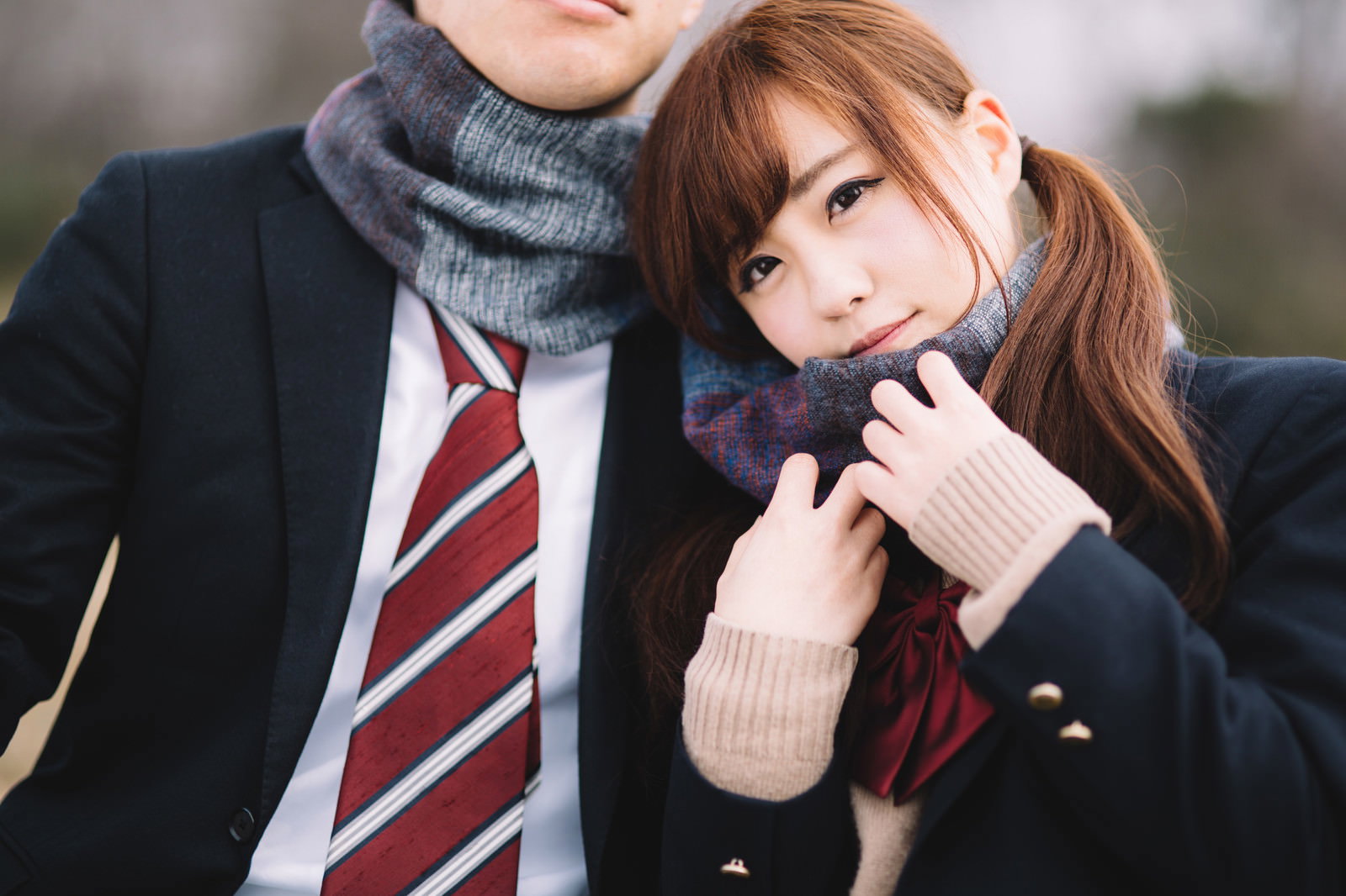 制服姿の女子高生と男性がマフラーを巻いて並ぶ［モデル：河村友歌］