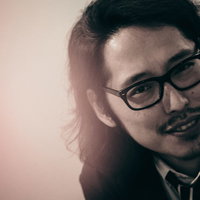 敏腕プロデューサーのオフショット、眼鏡姿で笑顔の男性の写真