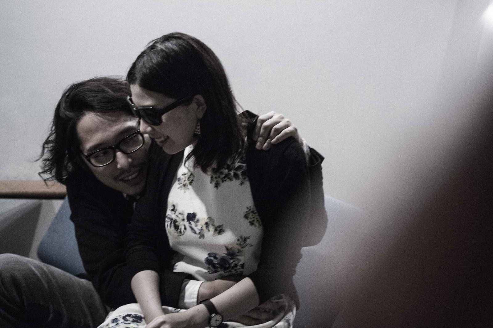 ソファーに座り肩を組む黒縁眼鏡の男性とサングラスの女性［モデル：ゆうせい］