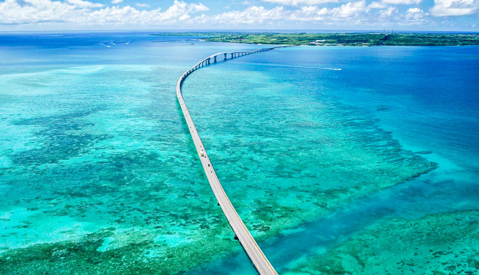 宮古島のエメラルドグリーンの海を一直線に渡る大橋をドローンで空撮した風景