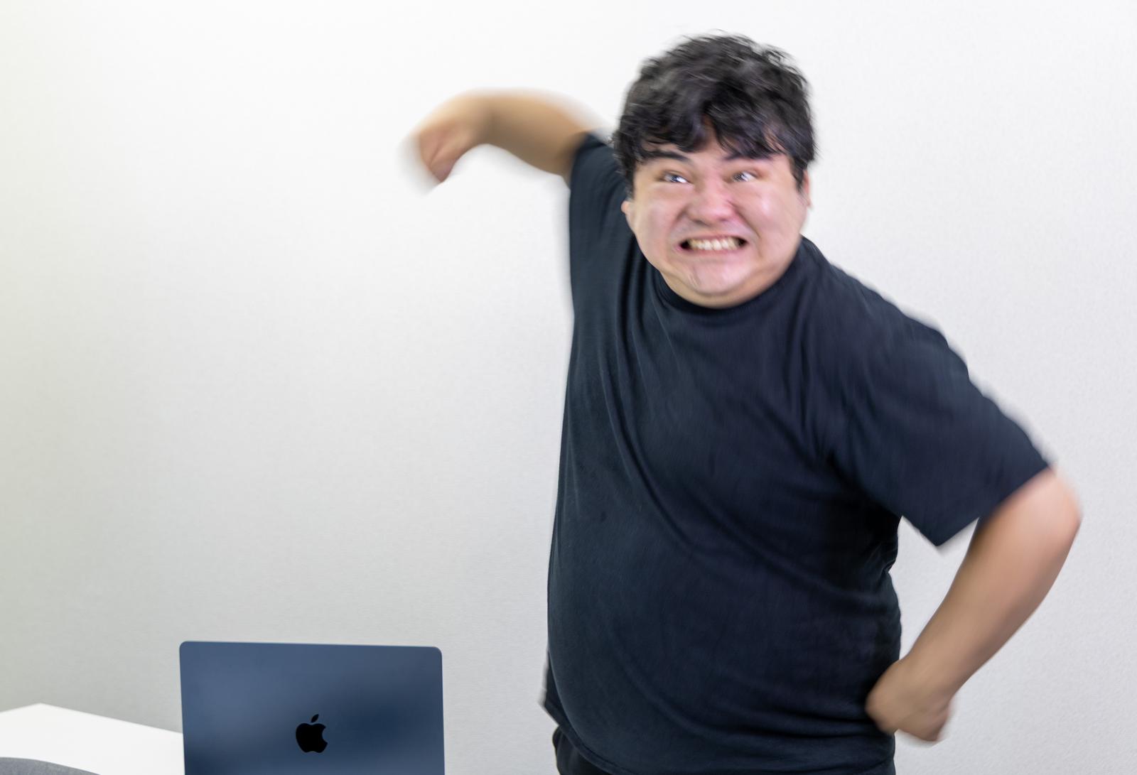 駄々をこねて机を強く叩く男性が口を開けて叫んでいる［モデル：段田隼人］