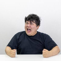 納得がいかないので机を叩く黒いTシャツの男性のの写真