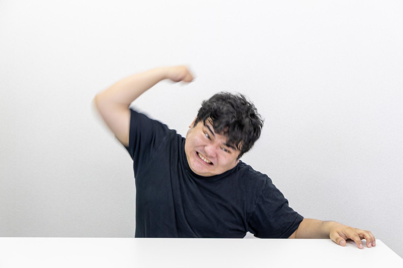 右腕を振り上げながら笑顔を見せる黒いTシャツの男性