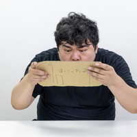 段ボールで作ったゲーム機で連打の練習を続ける男性の写真