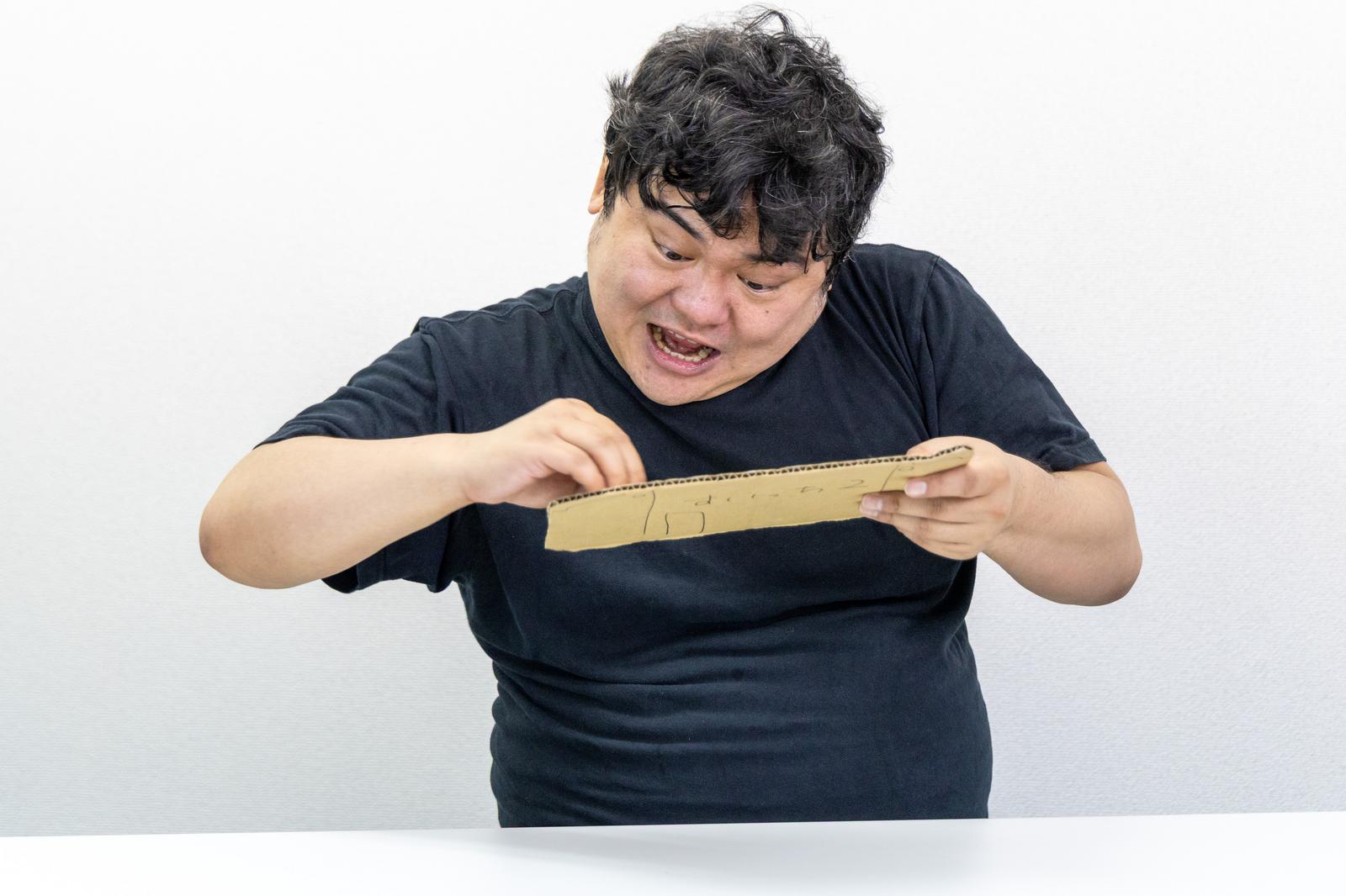 黒いTシャツを着た男性が前かがみになって笑顔で謝罪している