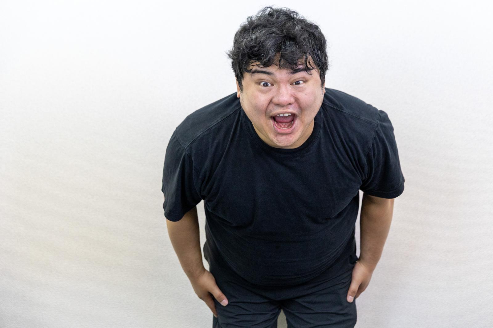 黒いTシャツの男性が前傾姿勢で謝罪している様子［モデル：段田隼人］
