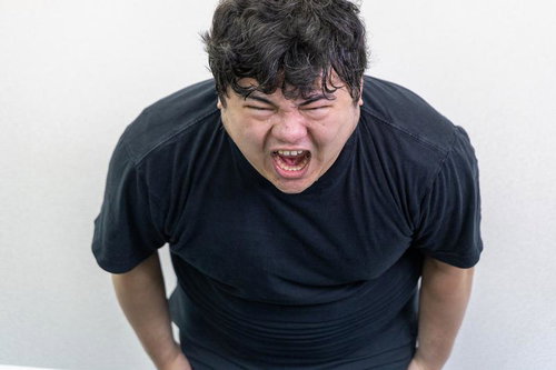 黒いTシャツを着た男性が前傾姿勢で激しく叫ぶポートレート