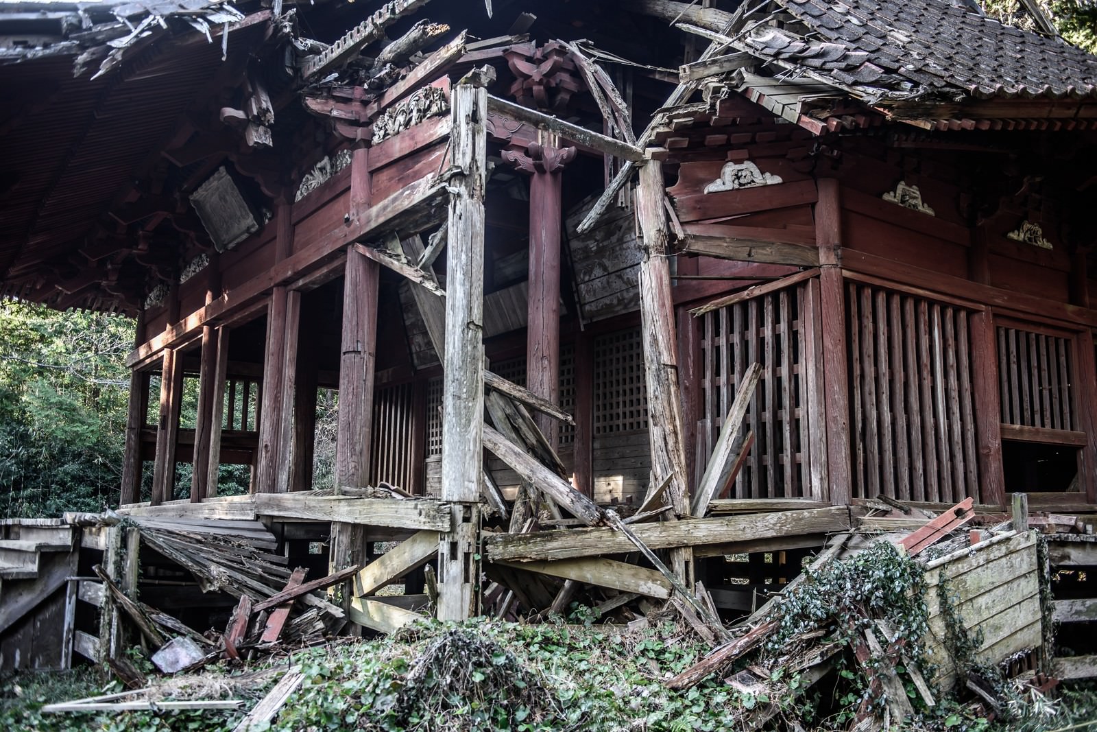 屋根や壁が崩れ落ちて荒廃した木造の古い寺院建築