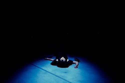 暗闇の中で膝を抱えて座り込む絶望の女性のシルエット