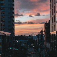 夕焼けに染まる駅前の街並み。高層ビルと夕方の空の写真