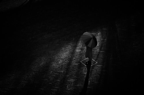 暗い背景に浮かぶパラソルと影のシルエット
