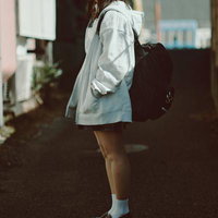 制服姿でリュックを背負い、通学路を歩く女子高生の横姿の写真