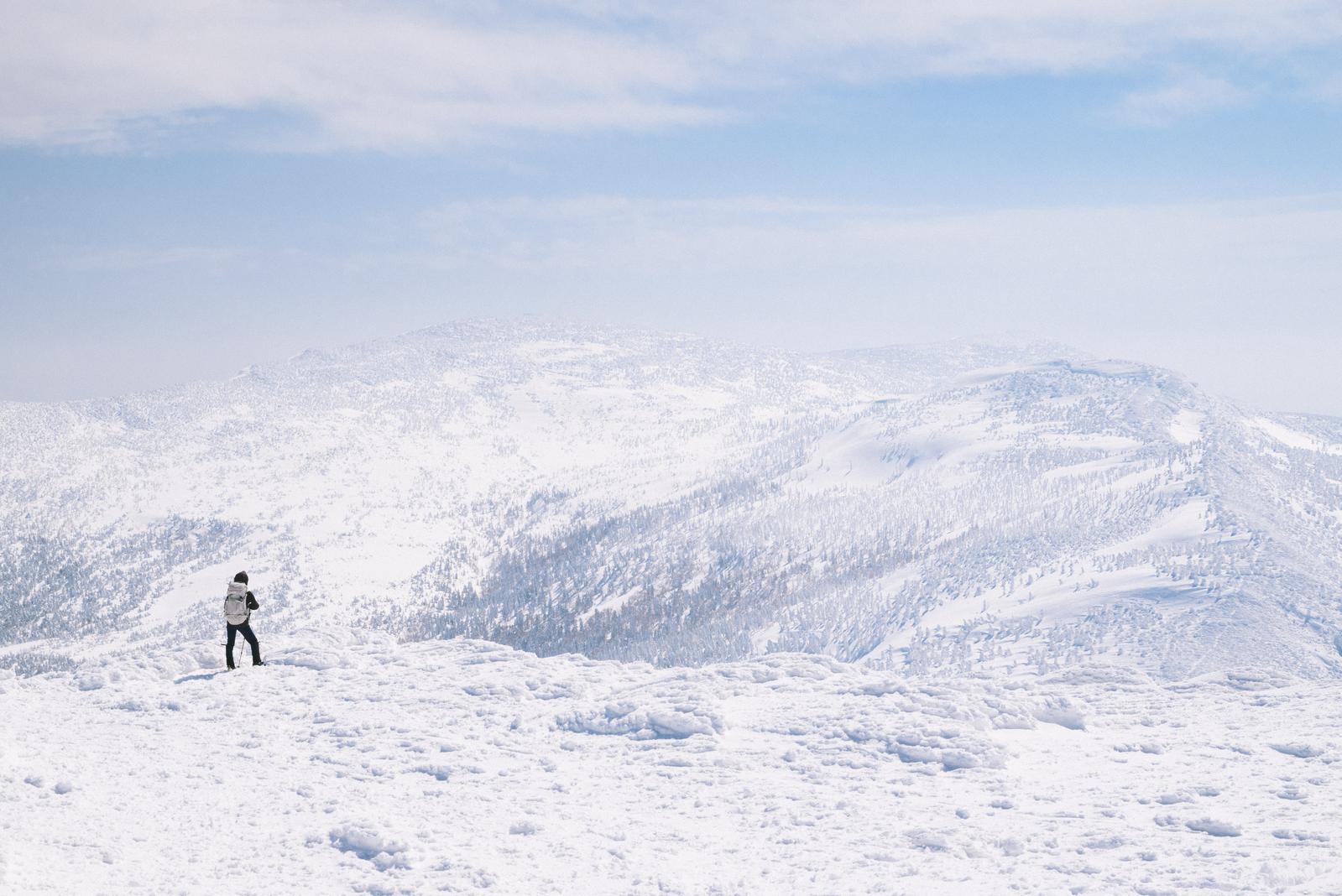 蔵王の屏風岳方面の樹氷林を眺めている登山者の写真
