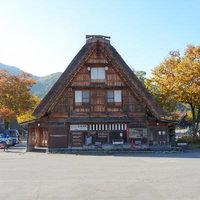 白川郷の駐車場横にある茅葺屋根の公衆便所と秋の紅葉の写真