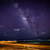 海辺の堤防から見上げる天の川と満天の星空の写真