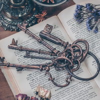 テーブルの上に広げた古書と古い鍵とドライフラワーのアンティーク静物の写真