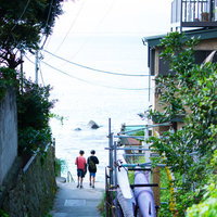 夏休みの路地裏を歩く少年たちの後ろ姿の写真