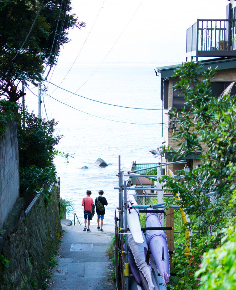 夏休みの路地裏を歩く2人の少年の後ろ姿