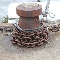 船着き場に錆び付く鎖が巻き付くボラード、係船柱の風景の写真